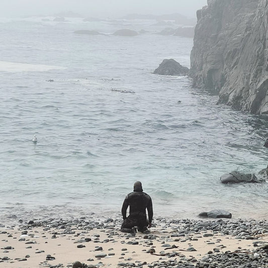Freediver giving thanks to the ocean on his knees in front of the water