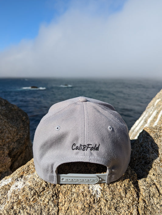 Cali8Fold casual snapback, grey, on a rocky outcropping, facing the ocean