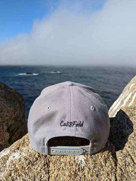 Cali8Fold casual snapback, grey, on a rocky outcropping, facing the ocean 
