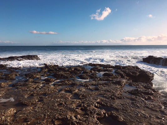 freediving location in Santa cruz, rocky shore with waves crashing on rocks, blue skies