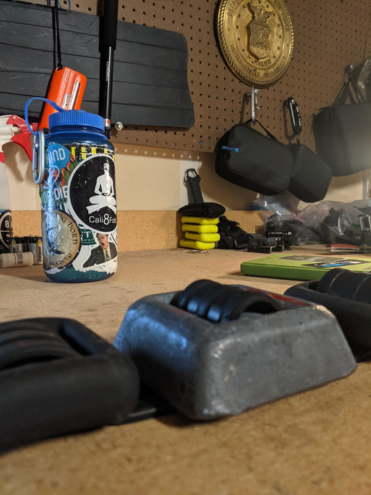 Picture of dive weight belt, with weight, in background is Nalgene bottle with Cali8Fold sticker, fins hung up background