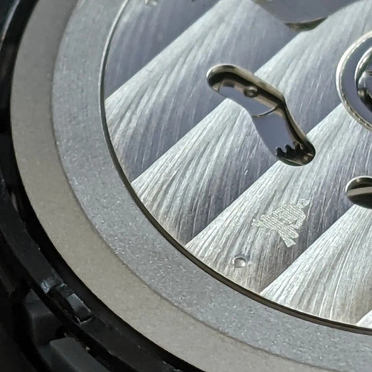 close up of back of watch, small engraving of crossed legged seated diver 